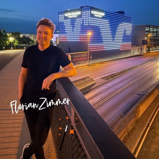 Florian Zimmer vor der Theaterfassade, beleuchtet im Volksbank-Design